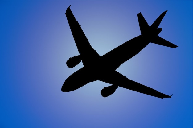 Low angle view of silhouette airplane against clear blue sky