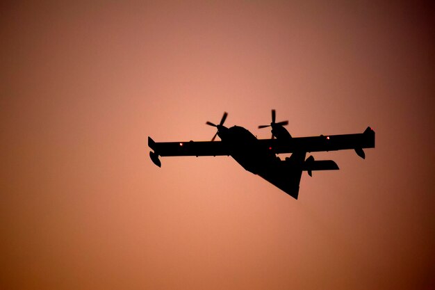 Photo low angle view of silhouette airplane against clear sky during sunset