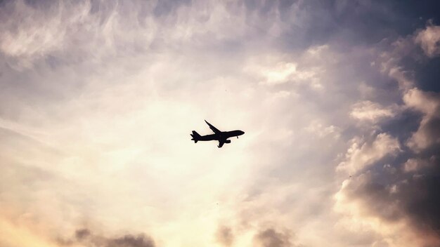 Low angle view of silhouette airplane flying against sky