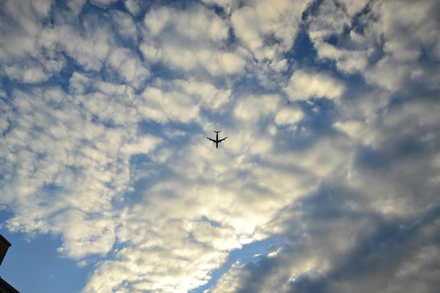 Foto vista a basso angolo di un aereo a silhouette che vola in un cielo nuvoloso