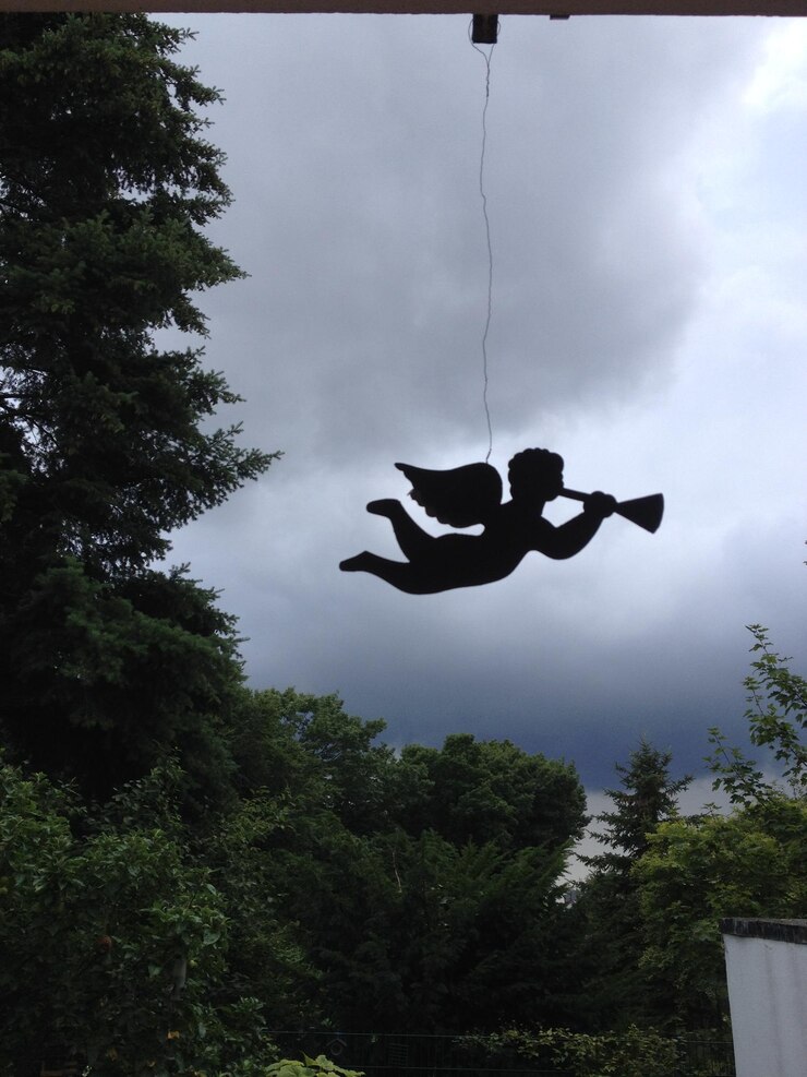 Photo low angle view of silhouette angel hanging against cloudy sky