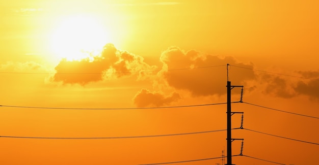 Low angle view of silhouette cables against orange sky