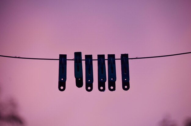 Photo low angle view of silhouette clothespins hanging on clothesline during sunset