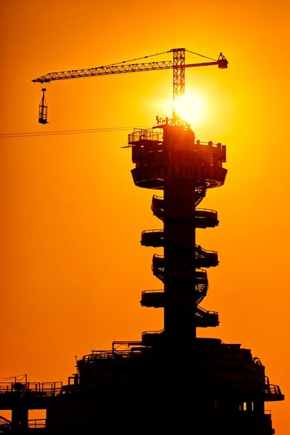 Low angle view of silhouette crane against sky during sunset