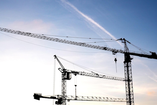 low angle view of silhouette cranes against sky at sunset