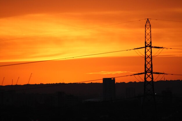 Low angle view of silhouette electricity pylon against romantic sky