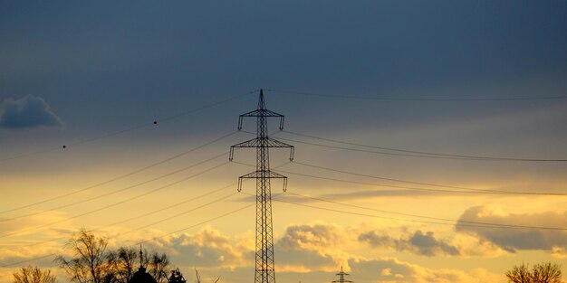 Low angle view of silhouette electricity pylon against romantic sky