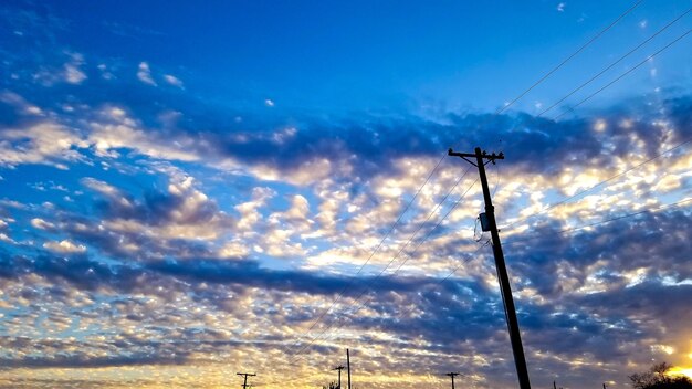 Low angle view of silhouette electricity pylon against sky during sunset