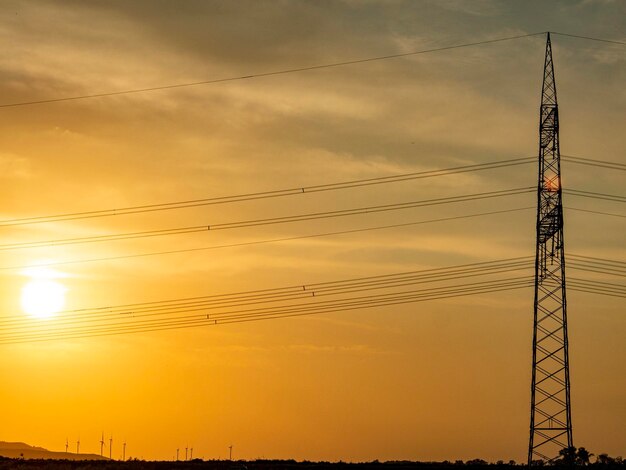 Low angle view of silhouette electricity pylon against sky during sunset