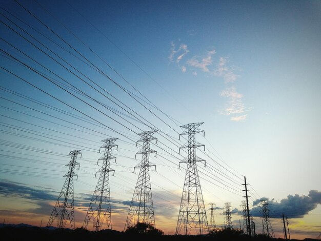 Low angle view of silhouette electricity pylon against sky during sunset