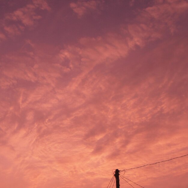 Low angle view of silhouette electricity pylon against sky during sunset