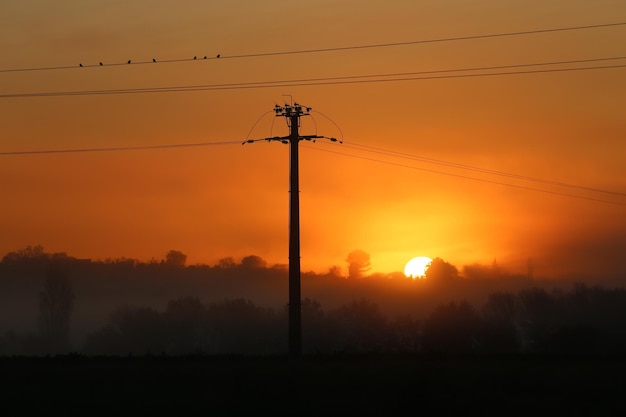 Low angle view of silhouette electricity pylon against sky during sunset