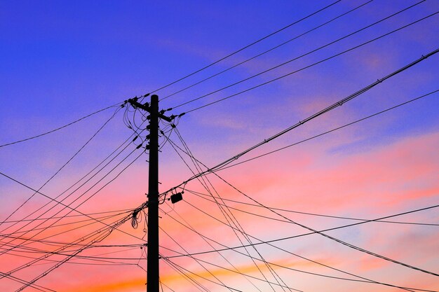 Low angle view of silhouette electricity pylon against sky