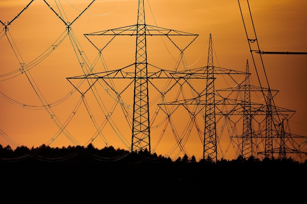 Low angle view of silhouette electricity pylon on field against sky during sunset