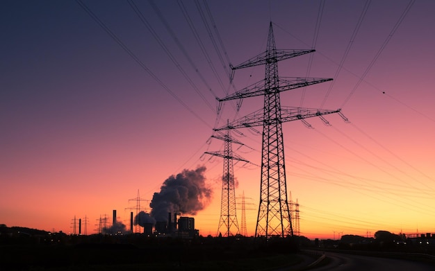 Low angle view of silhouette electricity pylons against clear sky