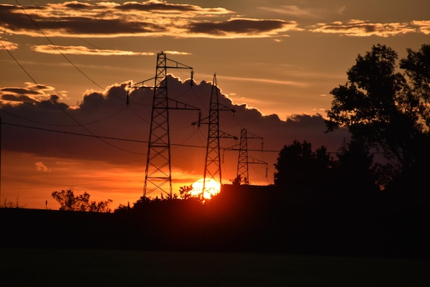 Photo low angle view of silhouette electricity pylons against sky during sunset