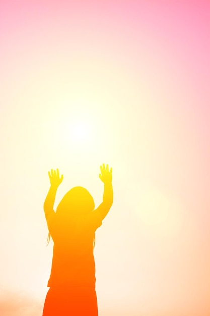 Low angle view of silhouette girl with arms raised standing against sky during sunset
