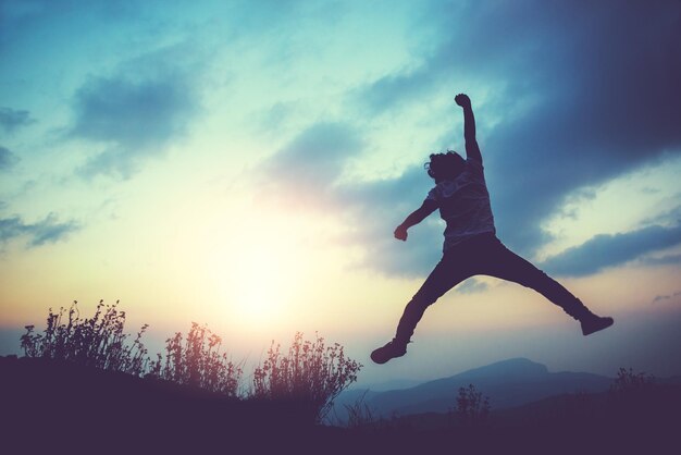 Low angle view of silhouette man jumping against sky during sunset