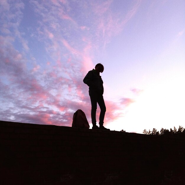 Low angle view of silhouette man standing against sky during sunset