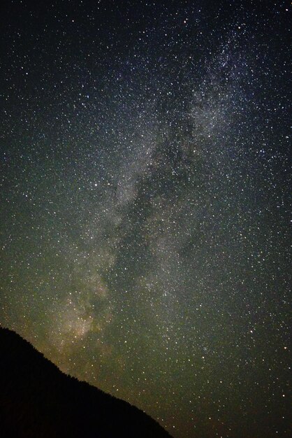 Low angle view of silhouette mountain against star field in sky at night