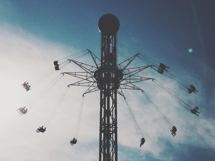 Photo low angle view of silhouette people enjoying chain swing ride against sky