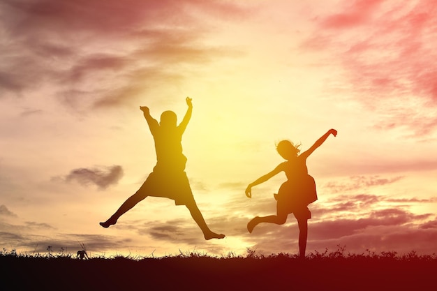 Low angle view of silhouette people jumping against sky during sunset