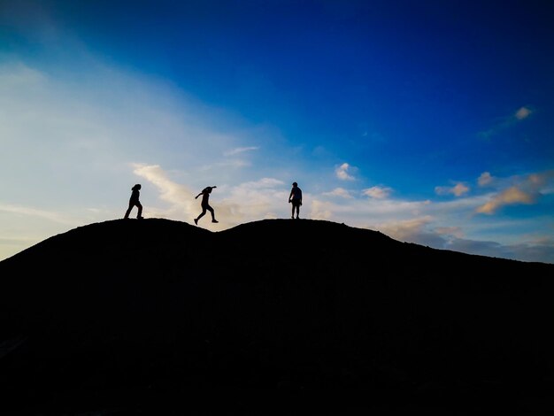 写真 空の向こうの土地に立っている人々の低角度のシルエット