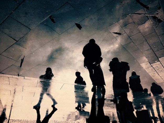 low angle view of silhouette people walking on wet road