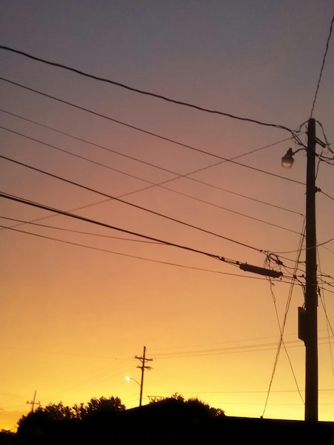 Foto vista a basso angolo delle linee elettriche di silhouette contro il cielo durante il tramonto