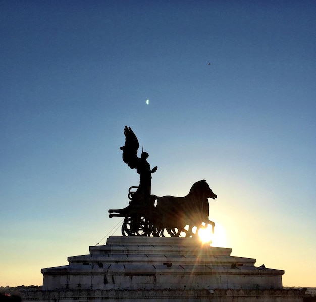 Low angle view of silhouette statue against clear sky