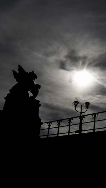 Foto vista a basso angolo della statua a silhouette contro il cielo nuvoloso durante il tramonto