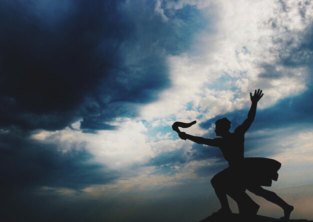 Foto vista a basso angolo della statua a silhouette contro un cielo nuvoloso