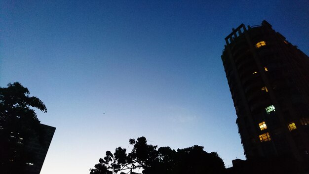 Low angle view of silhouette tower against blue sky