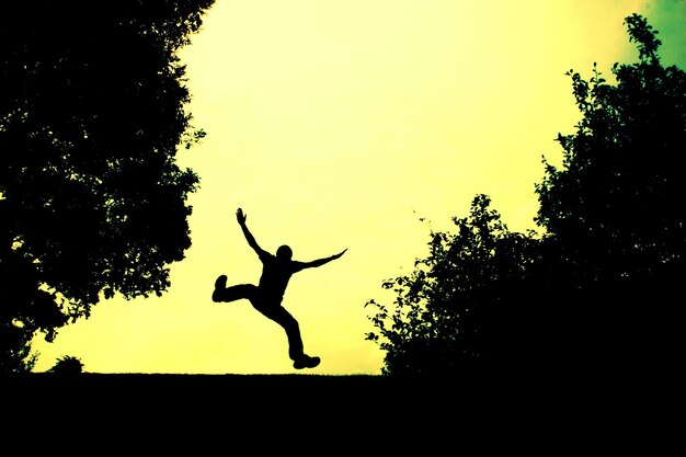 Photo low angle view of silhouette woman jumping in sky