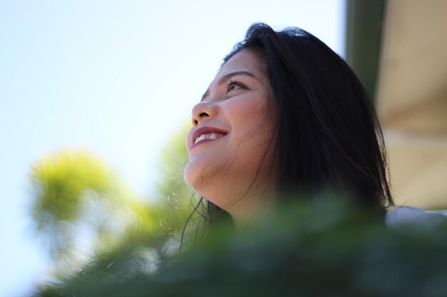 Photo low angle view of smiling thoughtful young woman looking away