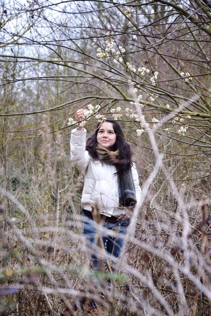 Low angle view of smiling young woman touching white flowers blooming on tree