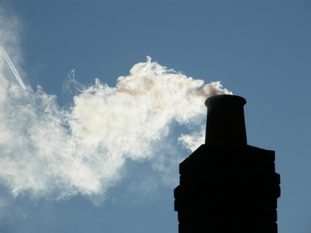 空に向かって工場から噴出する煙の低角度の視点