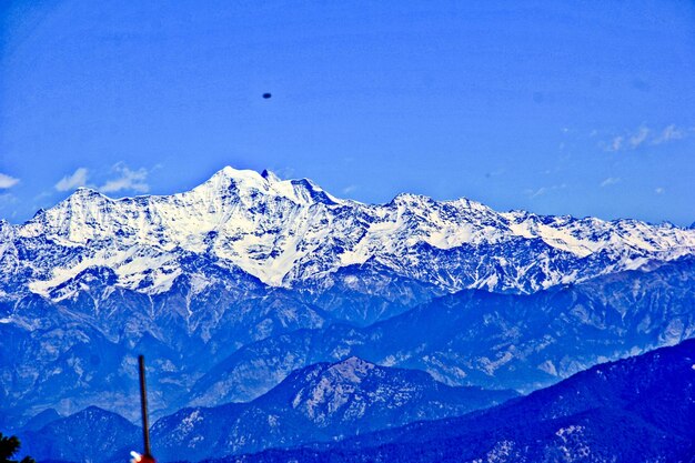 Low angle view of snow mountains against blue sky