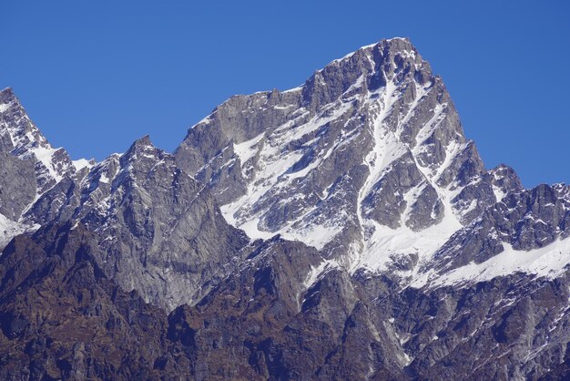 Low angle view of snowcapped mountain against blue sky