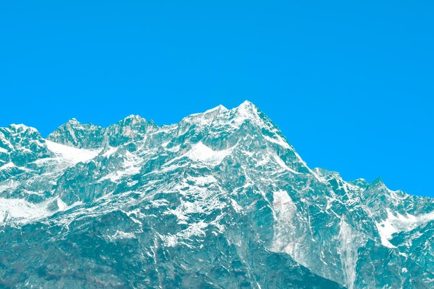 Low angle view of snowcapped mountain against clear blue sky