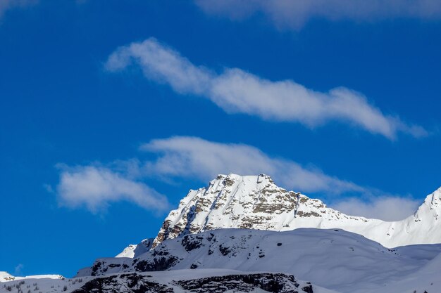 Low angle view of snowcapped mountains against blue sky