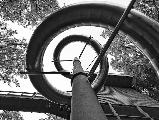 Low angle view of spiral slide pipe against sky