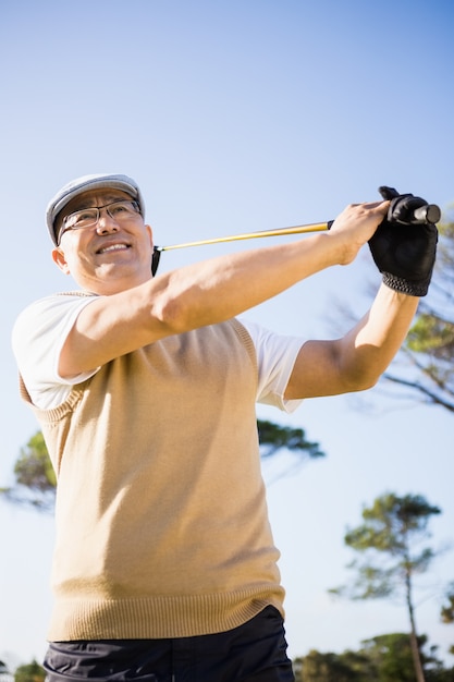 ゴルフをするスポーツマンの低角度のビュー