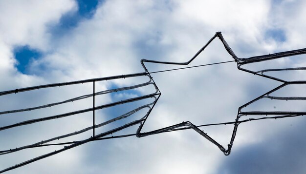 Low angle view of star shaped power cables against cloudy sky