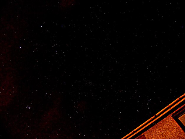 Low angle view of starry sky over building at night