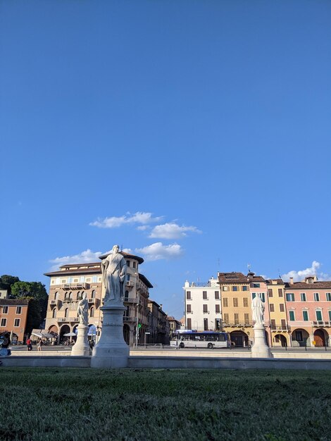 Low angle view of statue against buildings against clear blue sky