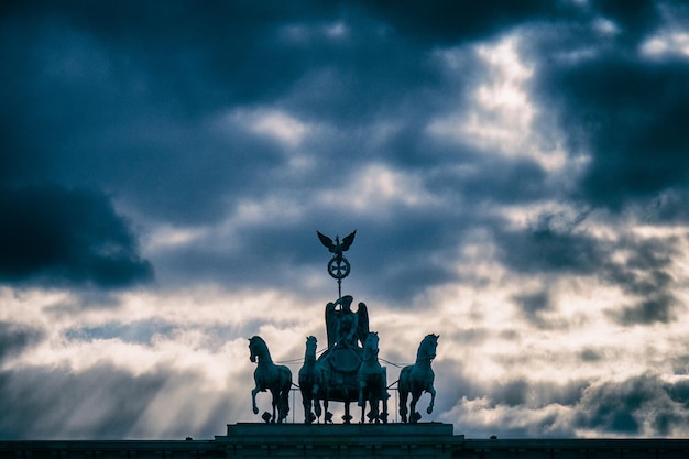 Photo low angle view of statue against storm clouds