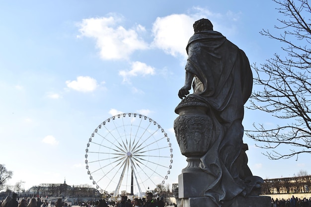 Photo low angle view of statue and ferris wheel against sky