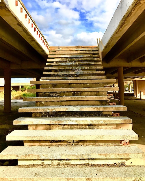 Photo low angle view of steps leading towards bridge against cloudy sky