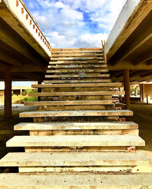 Foto vista a bassa angolazione dei gradini che conducono verso il ponte contro un cielo nuvoloso